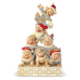 Snow White’s seven dwarfs reach new heights in their holiday decorating! Dressed in white robes and Santa caps, they form a garland-covered pyramid as Dopey tops the festive pile. This stone resin figurine is handcrafted and hand-painted.
